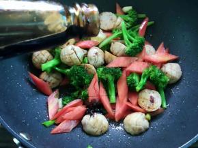 加入鱼丸、胡萝卜和西兰花翻炒几下，调入盐和蚝油炒匀