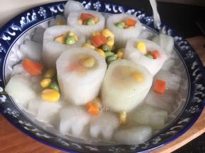 先把玉米粒、青豆、胡萝卜丁装入白萝卜空心内，多余的放在中间和周边，再倒入高汤