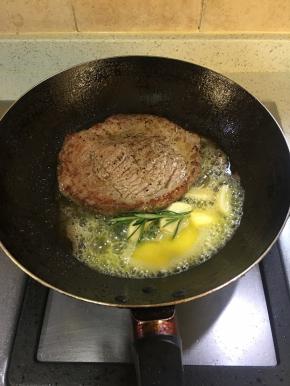 起锅烧热倒入油，煎牛排至4-5分钟，可以将牛排翻面，继续煎的同时，放入黄油、蒜头、和黄油。当黄油融化后，不停地往牛排上面浇黄油，煎至3-4分钟即可（5分熟）想吃老点的煎至5分钟即可不能再煎了