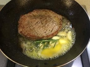 起锅烧热倒入油，煎牛排至4-5分钟，可以将牛排翻面，继续煎的同时，放入黄油、蒜头、和黄油。当黄油融化后，不停地往牛排上面浇黄油，煎至3-4分钟即可（5分熟）想吃老点的煎至5分钟即可不能再煎了