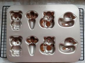 将可可色蛋糕糊装入剪了小口的裱花袋，在学厨WK9319金色八连蛋糕模的眼睛等部位，挤上少许蛋糕糊，入预热好的烤箱，上下火165度烤3-5分钟定型。