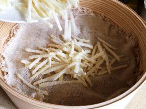 蒸屉铺上屉布，将拌均匀的土豆条直接倒在屉布上。