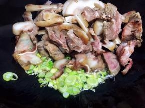 油锅烧热，放入肉块和葱碎翻炒片刻