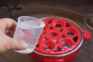 用小量杯往蒸蛋器的发热盘里倒入适量的水。