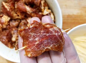 把腌制好的猪颈肉用牙签串起来，依次把所有猪颈肉串好