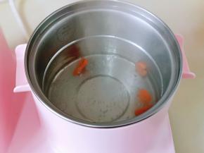 早餐机锅中加入水烧开，将4片胡萝卜焯水，煮1分钟捞出。