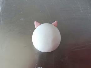 包入黑芝麻馅(这一步忘记拍照了)，用推的手法收口，滚圆后取适量红色面团做猪猪的耳朵，粘的时候刷一点点水就可以(说湿不湿的那种状态)，刷太多反而粘不住