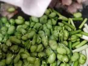 把炒熟的腊肉拔在锅边，倒入蒜薹和蚕豆，撒点点盐，不要太多，因为腊肉比较咸！