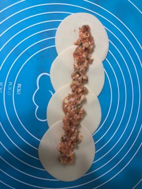 买现成的饺子皮，取四张按如图所示摆放，饺子皮中间放上馅料。