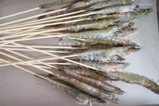 接下来就要串虾，把竹签尖端从虾尾部插入，慢慢往上推，到头的位置即可停住。