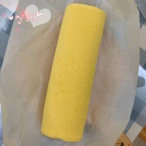 用擀面杖卷住油纸，顺势往上推，卷起来，两边跟拧糖一样拧起来。放入冰箱冷藏半小时后再切块食用。