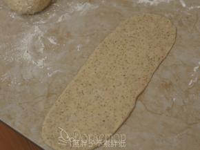 松弛好的面团压扁，用擀面杖擀成长方形面片。