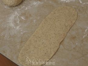 松弛好的面团压扁，用擀面杖擀成长方形面片。