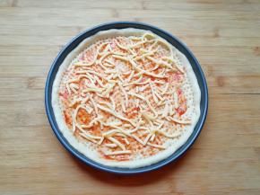 在饼底涂上一层番茄酱，撒上一层马苏里拉芝士。