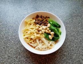 泡好的米线煮熟放入碗里，放入青菜、金针菇、豆腐皮和炒好的酸菜，最后放上花生米。