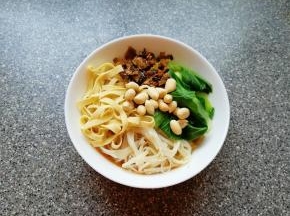 泡好的米线煮熟放入碗里，放入青菜、金针菇、豆腐皮和炒好的酸菜，最后放上花生米。