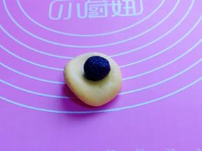 取一块小面团，包上豆沙馅，收口捏紧，揉圆。