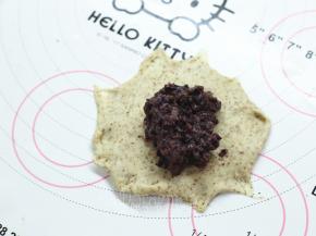 松弛好的面团压扁，用擀面杖擀成圆形面皮，边边用手指将面团压扁，这样待会更好粘合。中间放上紫米馅，我大约放了35g一个。