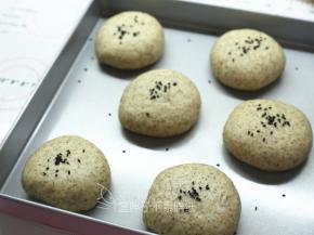 .取出发酵好的面团，表面撒上黑芝麻。