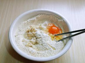将牛奶分次倒入面粉中，再磕入一个鸡蛋。