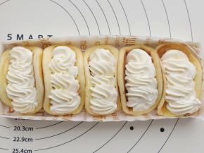 把蛋糕片弯曲地放在盒子里，挤上奶油。