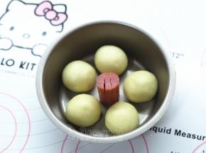 把做好的脆皮肠放在模具正中，这是花朵面包的花蕊。