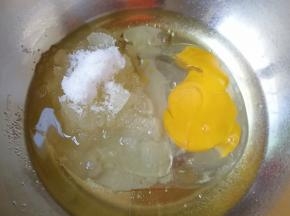 盆里倒入玉米油，加入细砂糖，打入一个鸡蛋。