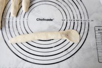 将收好的面团轻轻搓长至少二十厘米，将收口朝上，一头搓细，一头压扁擀扁。