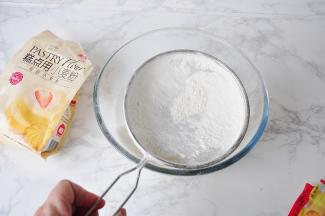 然后筛入低筋面粉和泡打粉，顺一个方向划圆拌匀，记往，不要过度搅拌，面粉无颗粒即可。面粉一定要记得过一下筛，这样才能保证面粉无颗粒。泡打粉大家一定要选用无铝泡打粉。