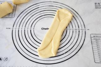 取其中一份，用擀杖擀成长舌养，对折一下。