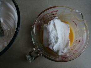 蛋清用电动打蛋器打至粗泡时，分两次加入剩余的细砂糖，打发至干性发泡的蛋白霜。取1/3打发好的蛋白霜打蛋黄糊里，从底部向上翻拌并切拌均匀