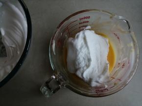 蛋清用电动打蛋器打至粗泡时，分两次加入剩余的细砂糖，打发至干性发泡的蛋白霜。取1/3打发好的蛋白霜打蛋黄糊里，从底部向上翻拌并切拌均匀