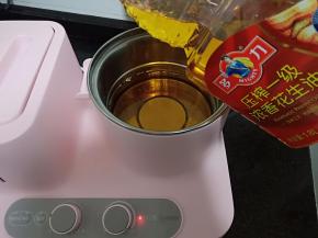 炸锅加热后倒入多力浓香花生油150毫升。