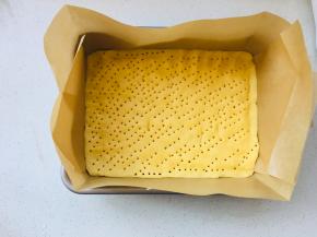 学厨9寸深烤盘模具中放置油纸，将擀好的面团放进模具中，四周压实，表面扎满孔