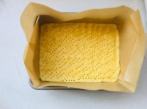 学厨9寸深烤盘模具中放置油纸，将擀好的面团放进模具中，四周压实，表面扎满孔