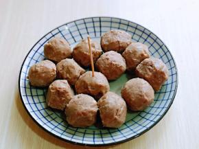 将牛肉丸子从包装中取出，用温水冲洗，放入盘中，再用牙签扎满洞洞眼，便于入味。