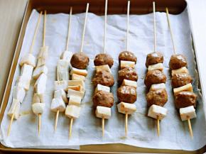 串好牛肉丸子串放入垫有油纸的烤盘中，刷上胡椒油。