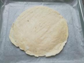 烤盘里铺上油纸，放上一张手抓饼饼胚(无需解冻)。