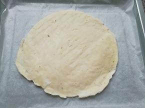 烤盘里铺上油纸，放上一张手抓饼饼胚(无需解冻)。