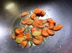 锅内放油烧热，放入胡萝卜片和生姜片翻炒片刻