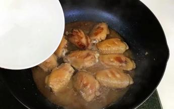 把鸡翅两面煎至金黄色，加入与鸡翅齐平的开水，稍搅动均匀。