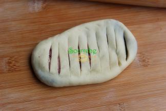 包好的面团收口朝下，放在案板上用擀面杖擀成长椭圆形。用小刀在长椭圆形上划斜刀纹，划到蓝莓馅即可，不用完全划穿。 擀面团是时候，周边容易破，露馅，这个时候，馅料中间有空气，不要往边缘擀的太用力。