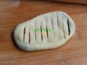 包好的面团收口朝下，放在案板上用擀面杖擀成长椭圆形。用小刀在长椭圆形上划斜刀纹，划到蓝莓馅即可，不用完全划穿。 擀面团是时候，周边容易破，露馅，这个时候，馅料中间有空气，不要往边缘擀的太用力。