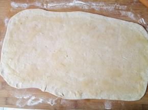 发酵好的面团充分揉匀排气，放置十分钟松弛一下，擀成一个方形的大面片，油酥用勺子背涂抹均匀。