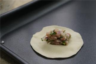 将拌好的馅料夹放在饺子皮中间。
