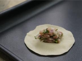 将拌好的馅料夹放在饺子皮中间。
