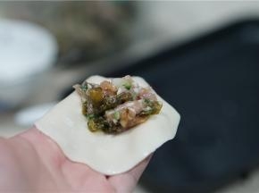 将拌好的馅料包在饺子皮里。