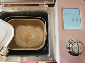 依次放入水、蛋液、糖、盐、奶粉和面包粉，在面粉顶端加入酵母，将面包桶放入到东菱JD08面包机里，选择和面程序10分钟