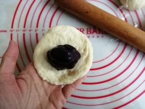 将面团擀圆，翻面，光滑面朝下，放入搓成圆形的30克紫薯馅