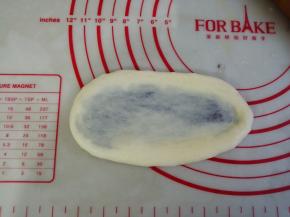 将面团略用手压扁后，用擀面棍擀成椭圆形